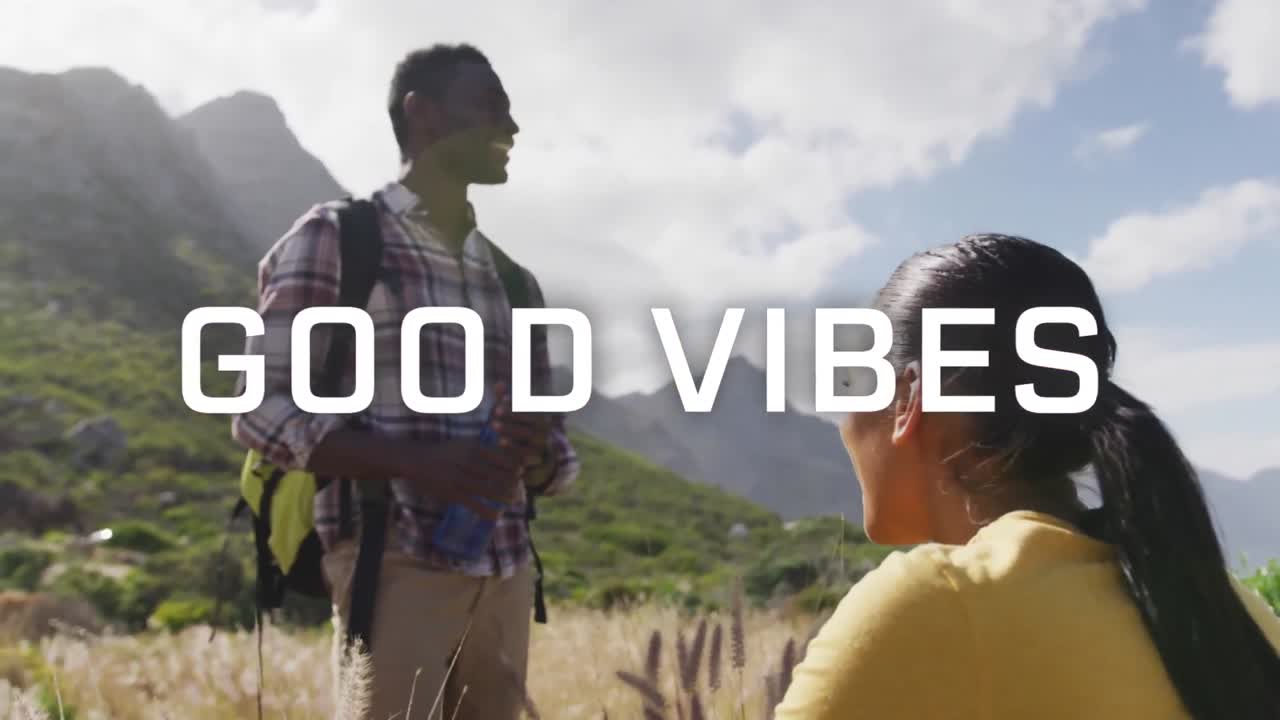 animación de las palabras buenas vibraciones escritas en blanco sobre una pareja caminando en las montañas tomando un descanso