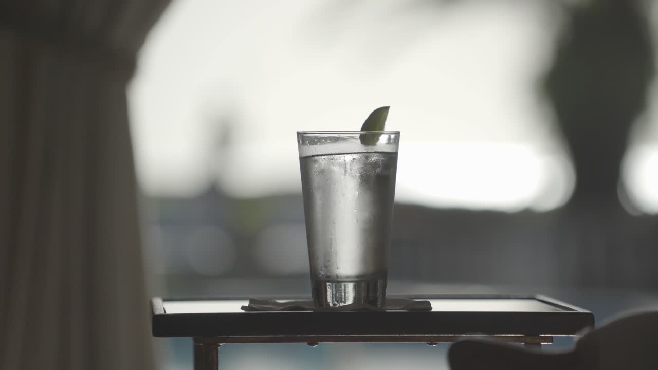 웨이터가 나무 테이블에 놓은 음료, 물, 진 토닉 또는 보드카 소다와 얼음 큐브와 라임