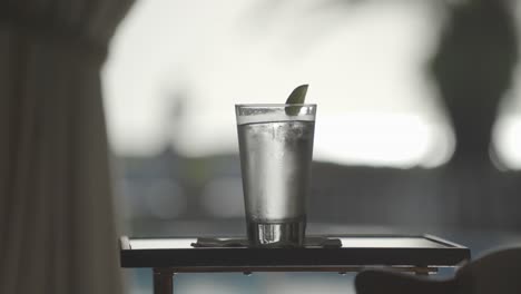 beverage being set on wooden table by waiter, water, gin tonic or vodka soda with ice cubes and lime