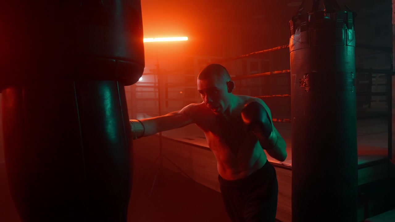 Pugile si allena con sacco da boxe in palestra buia con luci al neon