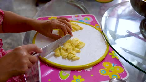 female cut delicious pineapple into small pieces on cutting board