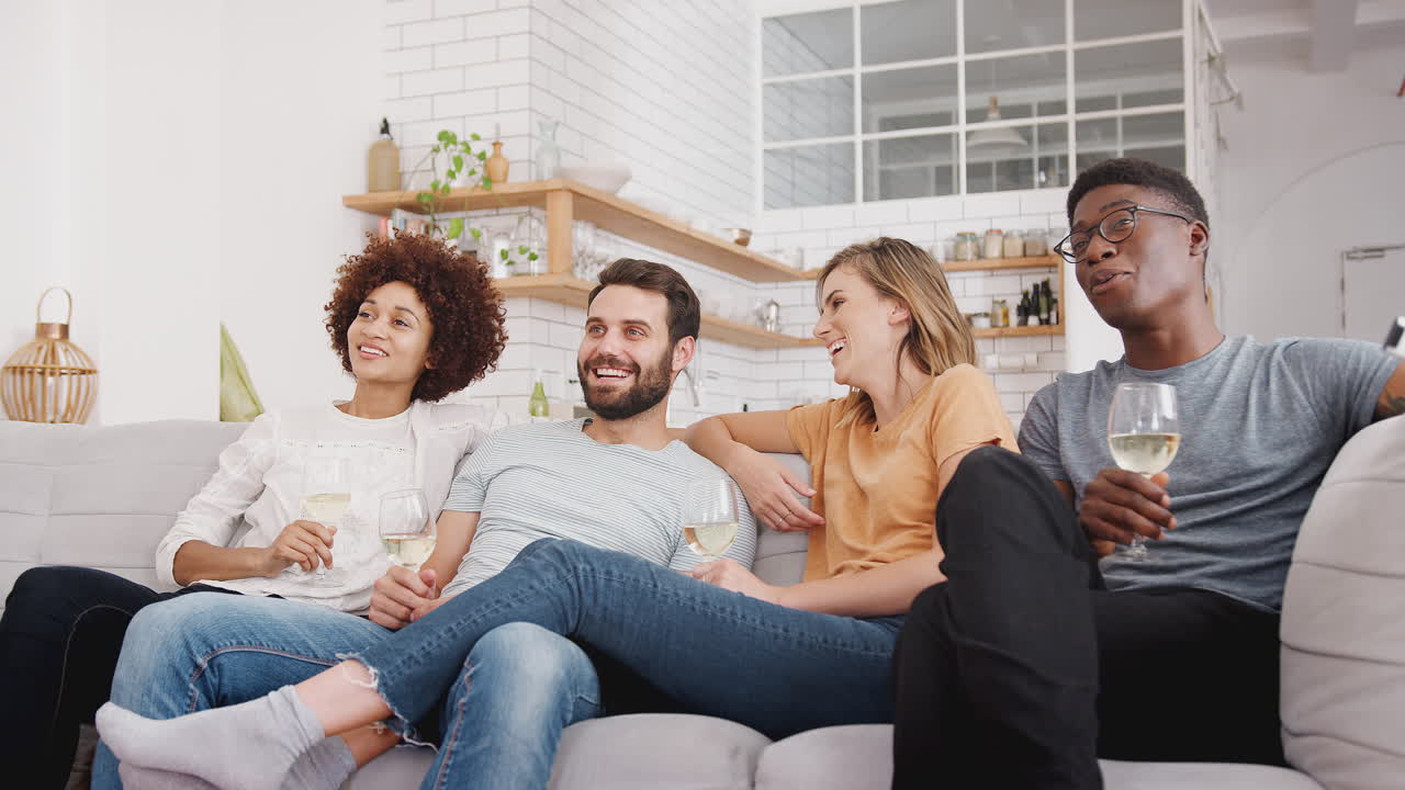 친구 들 이 소파 에 앉아 와인 을 마시면서 집 에서 영화 를 보고 있다