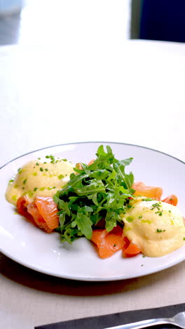 classic eggs benedict featuring smoked salmon and fresh arugula rotating slowly on pristine white plate, showcasing elegant culinary presentation with gourmet breakfast details