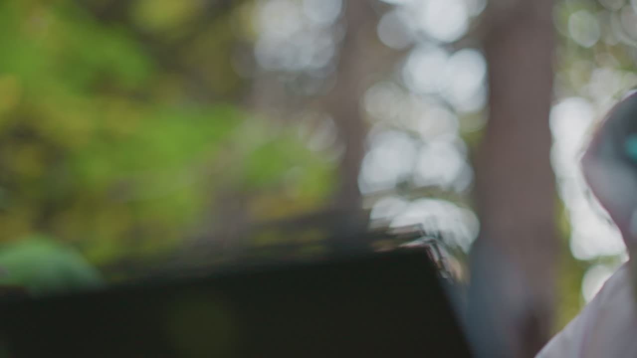 close up of botanist with polished nails gently inspecting vibrant pink flower and holding green leaf while using pen during detailed field study with blurred natural background