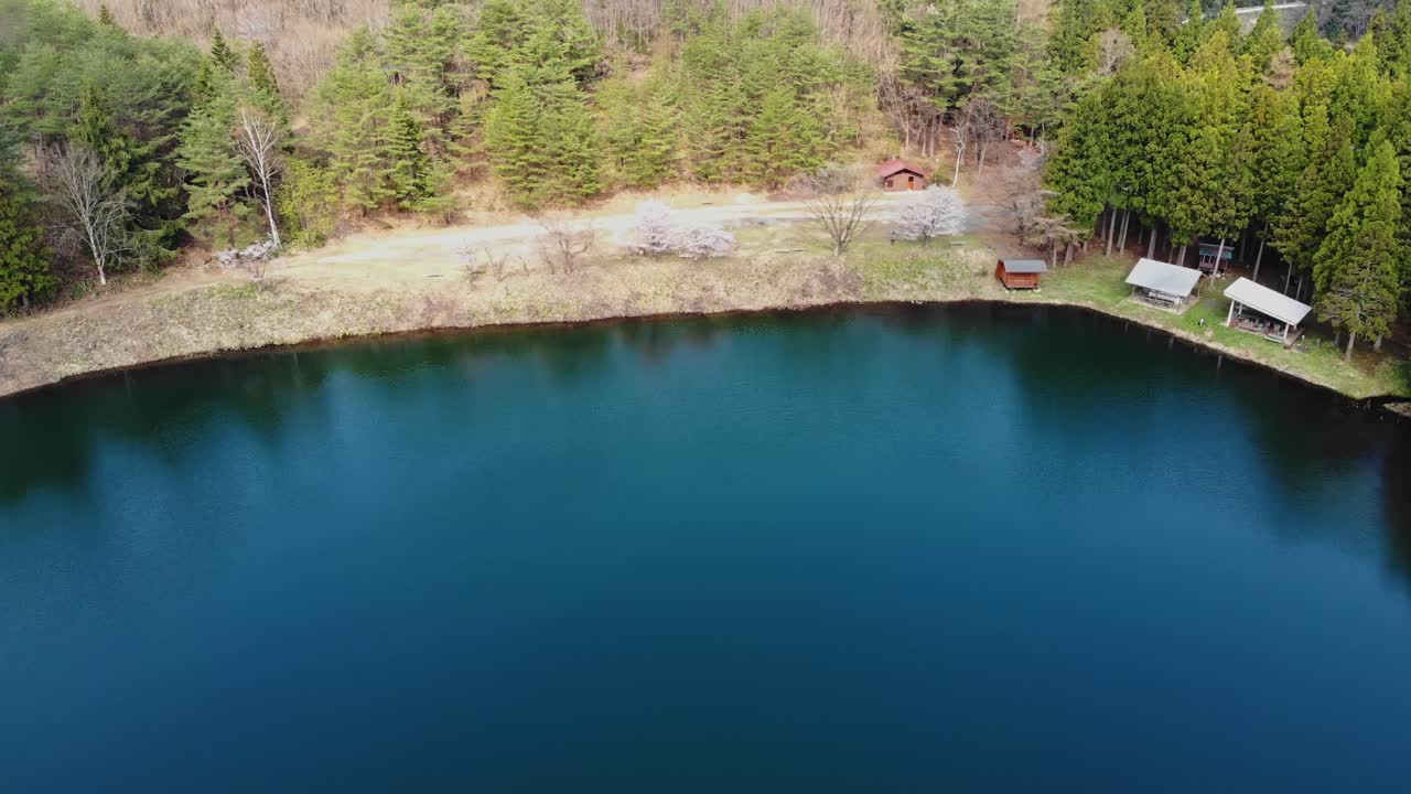 Aerial rise up above Yamagata lake coastline, countryside forested location in Japan in top of Mount Zaō