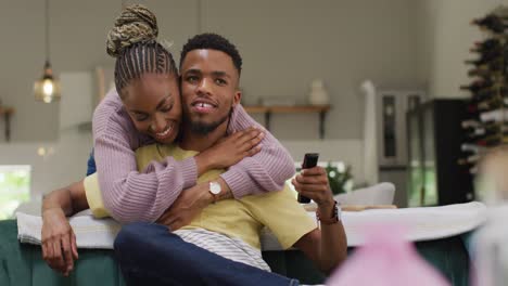 Glückliches-Afroamerikanisches-Paar,-Das-Auf-Dem-Sofa-Redet-Und-Sich-Umarmt