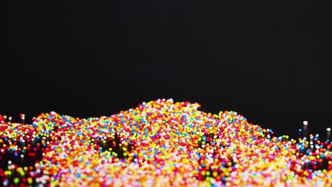 vibrant sprinkles cascade onto a dark surface