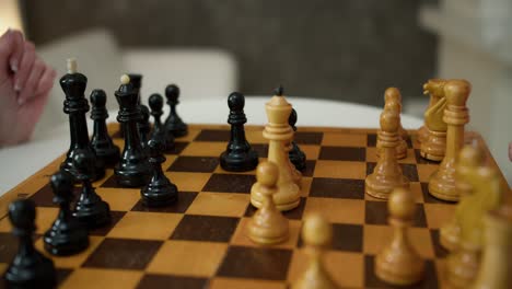 Old-female-hand-playing-chess-with-kid-at-home-close-up