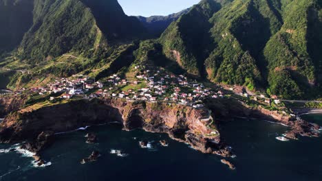 Aerial-view-of-a-city-on-a-rocky-volcanic-green-coast,-Seixal,-Madeira