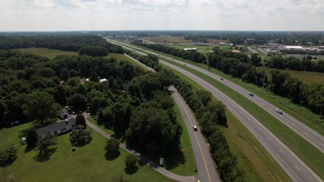 an aerial view of a curved road by farmland with many trees separating them