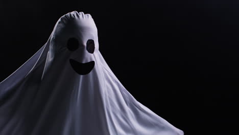 child dressed up in ghost costume trick or treating at halloween scaring people in front of black studio background 1