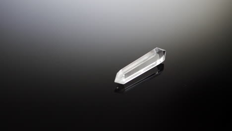 a clear see through crystal for alternative medicine healing with light shining bright isolated on a black reflection background