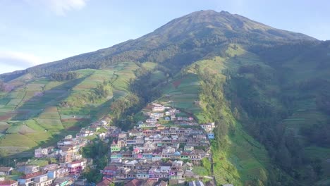 Vista-Aérea-De-La-Montaña-Con-Un-Hermoso-Pueblo-En-La-Ladera-En-La-Mañana-Ligeramente-Nublada