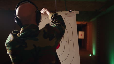 man in firing range shooting targets with pistol, wearing earmuffs