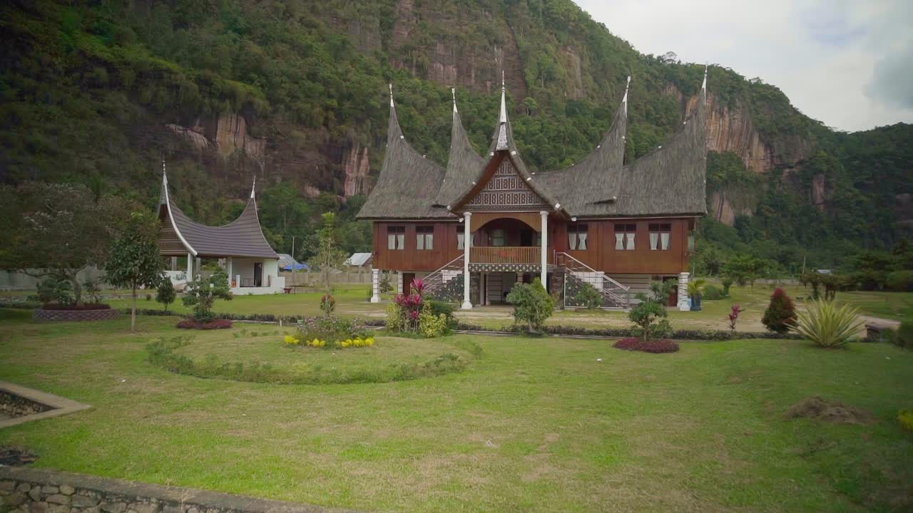 A traditional West Sumatra home nestled against a dramatic cliff in rural Indonesia. This shot highlights the unique architecture and stunning natural surroundings.