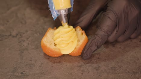 pastry chef applies custard on cupcake lying on table