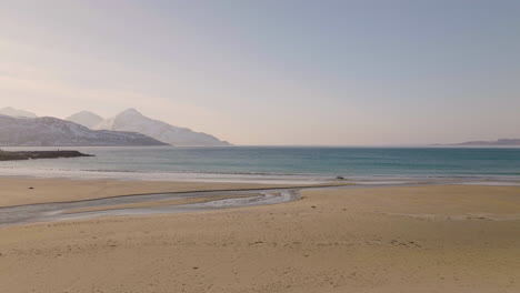 rippling waves coming toward the shores of grotfjord beach kvaloya northern norway - forward dolly drone shot