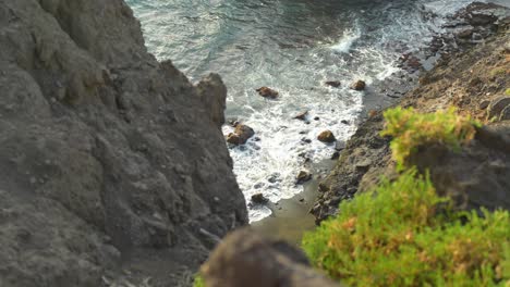 Top-down-view-of-ocean-waves-crashing-into-rocks-in-Los-Gigantes,-Tenerife