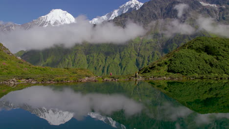 paisaje de nepal disparado por un avión no tripulado colinas verdes y nubes de montaña, chica caminando con un sari rosa, reflejo del lago 4k