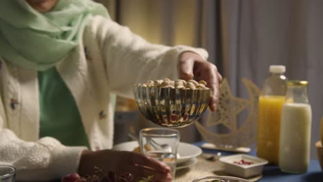 woman wearing hijab at muslim family table at home eating iftar meal breaking daily fast during ramadan