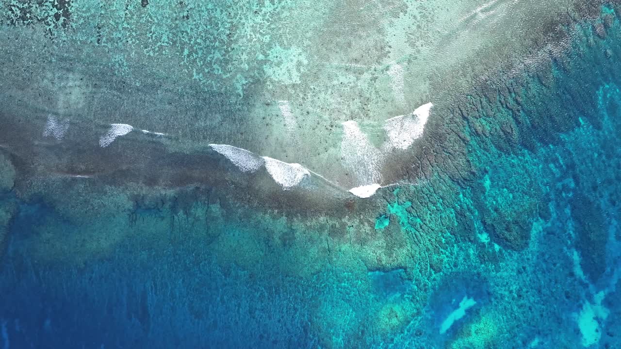 "A stunning aerial drone shot capturing the calm and crystal-clear emerald waters of Saipan’s west coast. Features beautiful coral reefs visible through the transparent sea."