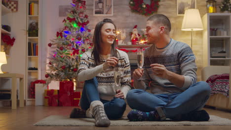 pareja alegre en el día de navidad sosteniendo fuegos artificiales en la mano