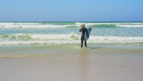 Rückansicht-Einer-Aktiven-älteren-Kaukasischen-Surferin,-Die-In-Der-Sonne-Auf-Dem-Meer-Läuft-4k