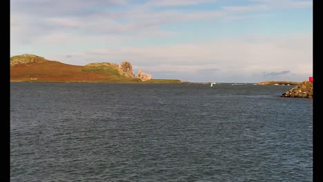Drone-video-of-Howth-Harbour,-panning-from-left-to-right-from-Ireland's-Eye-to-the-Harbour-wall-Lighthouse