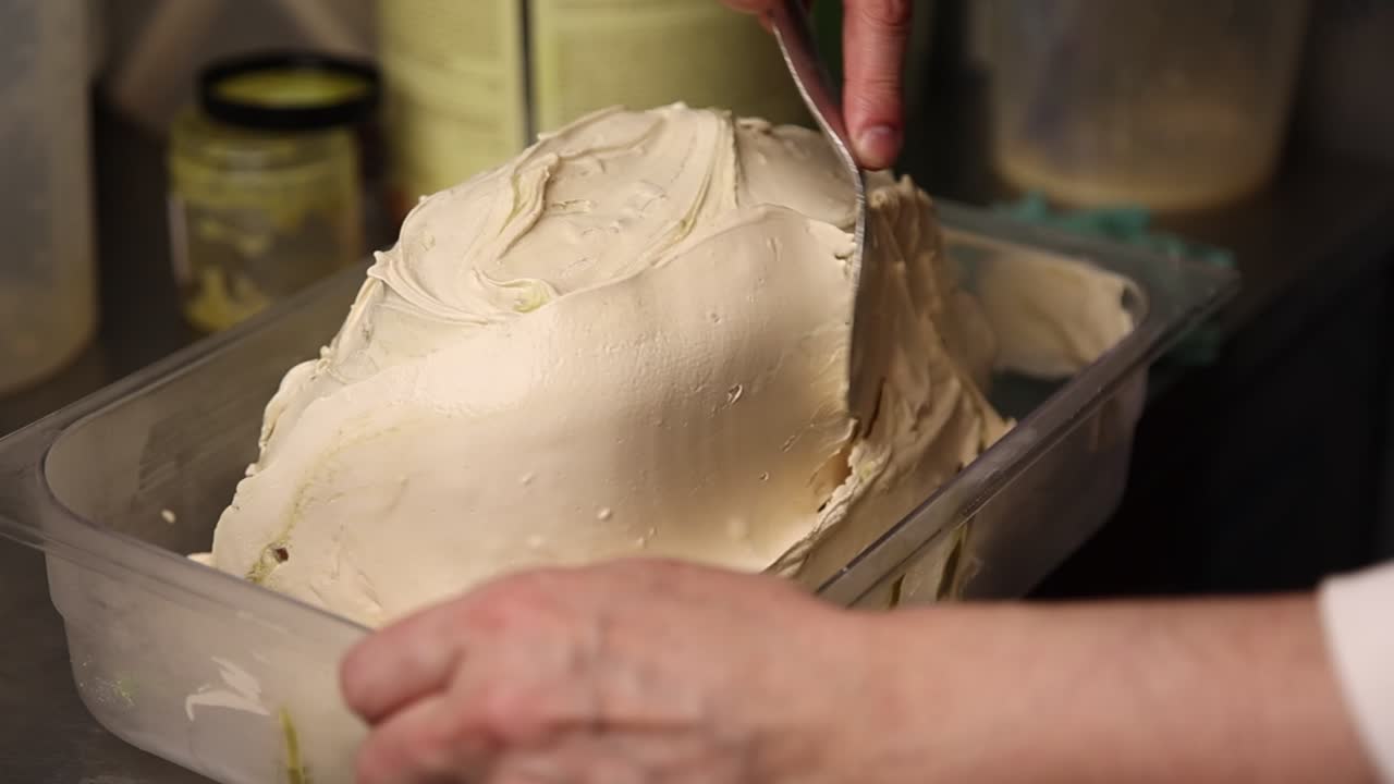 Close-Up of Hands Scooping Creamy Gelato from Container