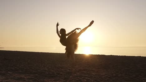 Silueta-De-Una-Bailarina-Con-Tutú-Y-Zapatillas-De-Punta-En-La-Orilla-Del-Mar.-Practicando-Movimientos-Y-Poses-De-Ballet.-Rayos-De-Sol-De-La-Mañana-Alrededor-Del-Elegante-Cuerpo-De-Bailarina-De-Ballet.-Camara-Lenta