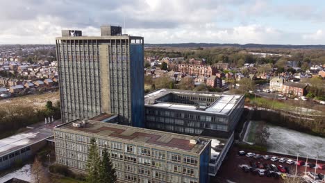 aerial view pilkington's glass head office, a modern blue high-rise with shared office space, pull back shot