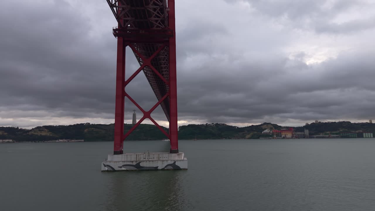 Underside of Ponte 25 de Abril road and rail bridge over Tagus river under an overcast sky, Lisbon