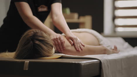 relaxation in modern spa salon masseuse is massaging back of female visitor of manual therapy clinic