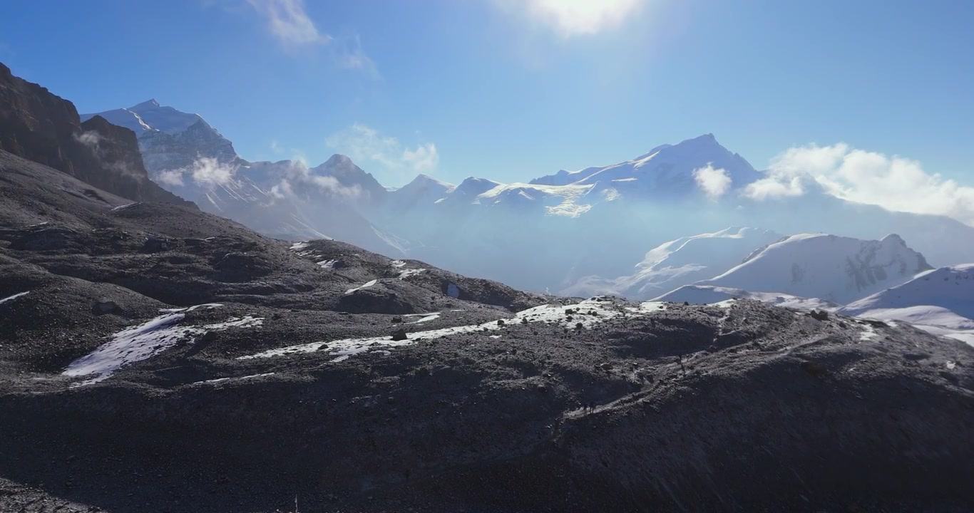 Thorong La Pass, Annapurna Circuit, Manang, Nepal, drone svæver over barskt bjergterræn mod sneklædte Himalaya-toppe i tidligt morgenlys