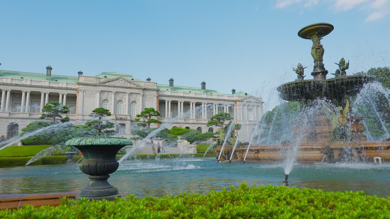 Vista del Palacio de Akasaka y su fuente principal, enmarcada por una fuente ornamental más pequeña y vegetación en primer plano