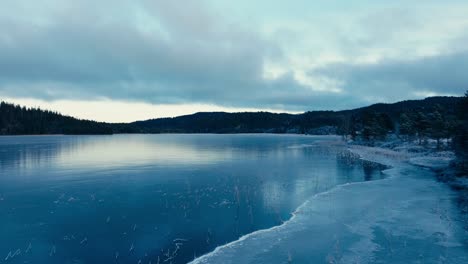 indre fosen, trondelag county, norway - the icy surface of omundvatnet and its mirrored reflection - drone flying forward