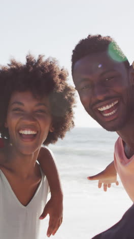 portrait of smiling african american family embracing on sunny beach