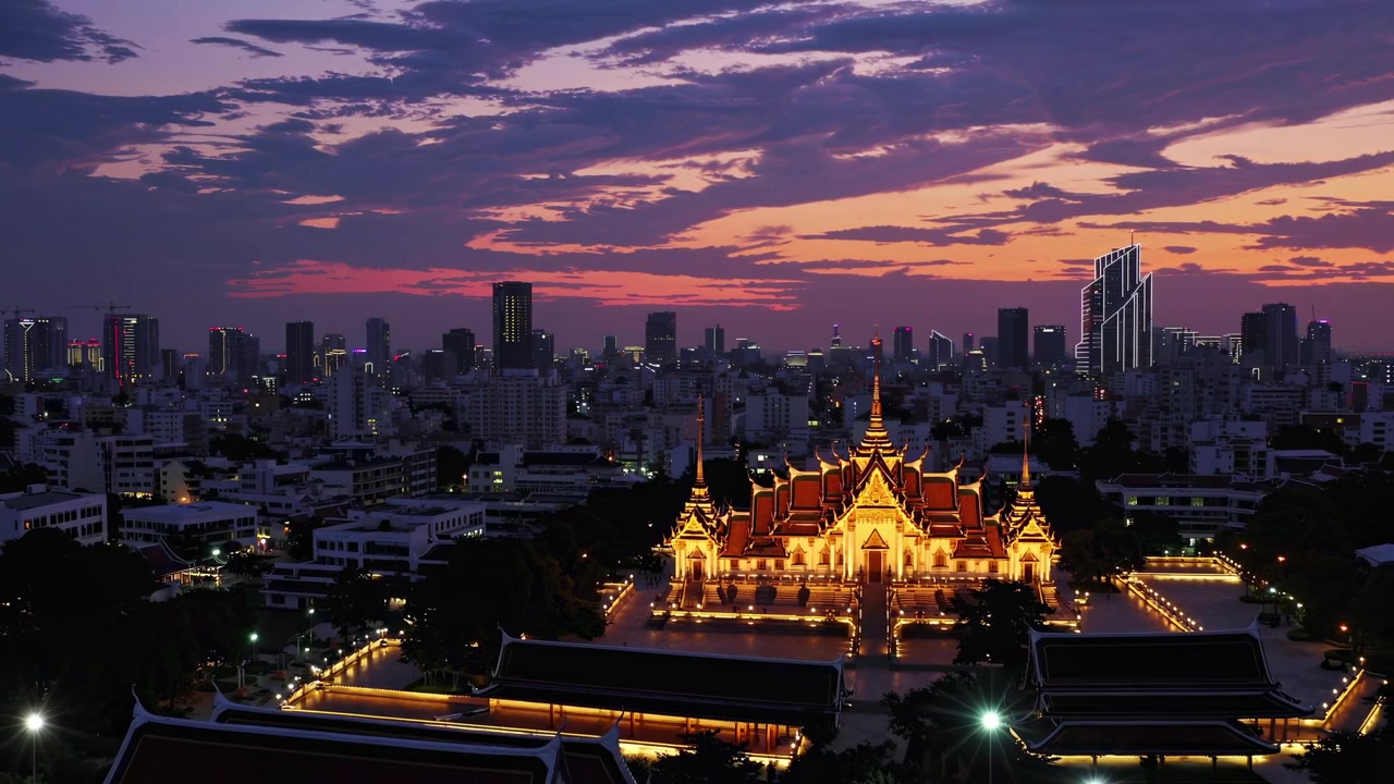 Illuminated Loha Prasat Temple and Bangkok City Skyline at Dusk