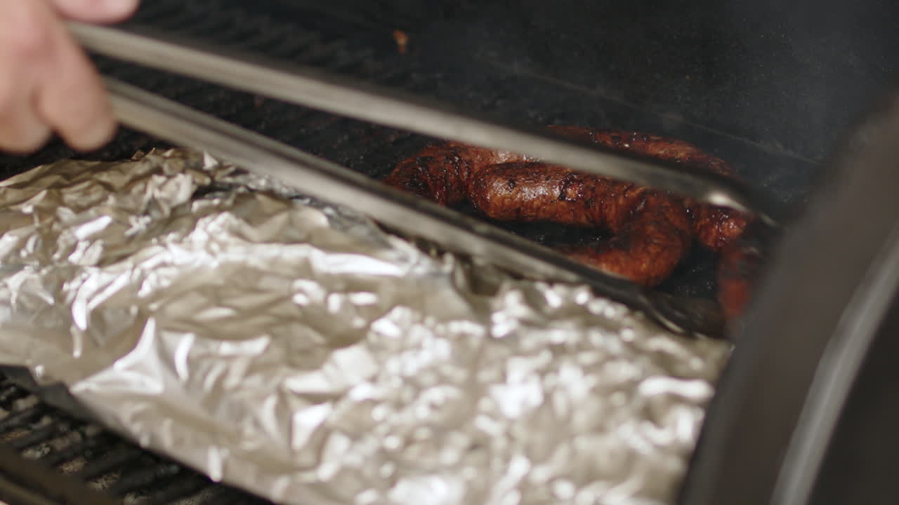 la salchicha de barbacoa se está moviendo de la parrilla de fumar a la tabla de corte en cámara lenta