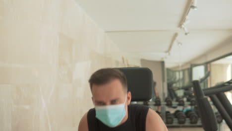 strong male with face mask lifts weights and exercises in the gym