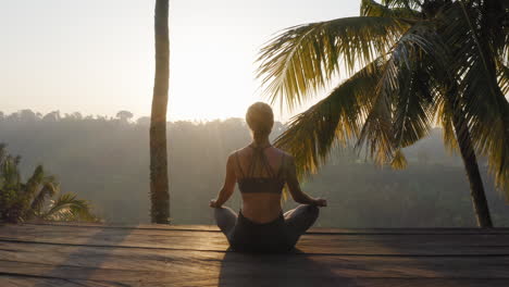 yoga woman meditating at sunrise practicing mindfulness meditation exercise sitting on deck outdoors in nature 4k