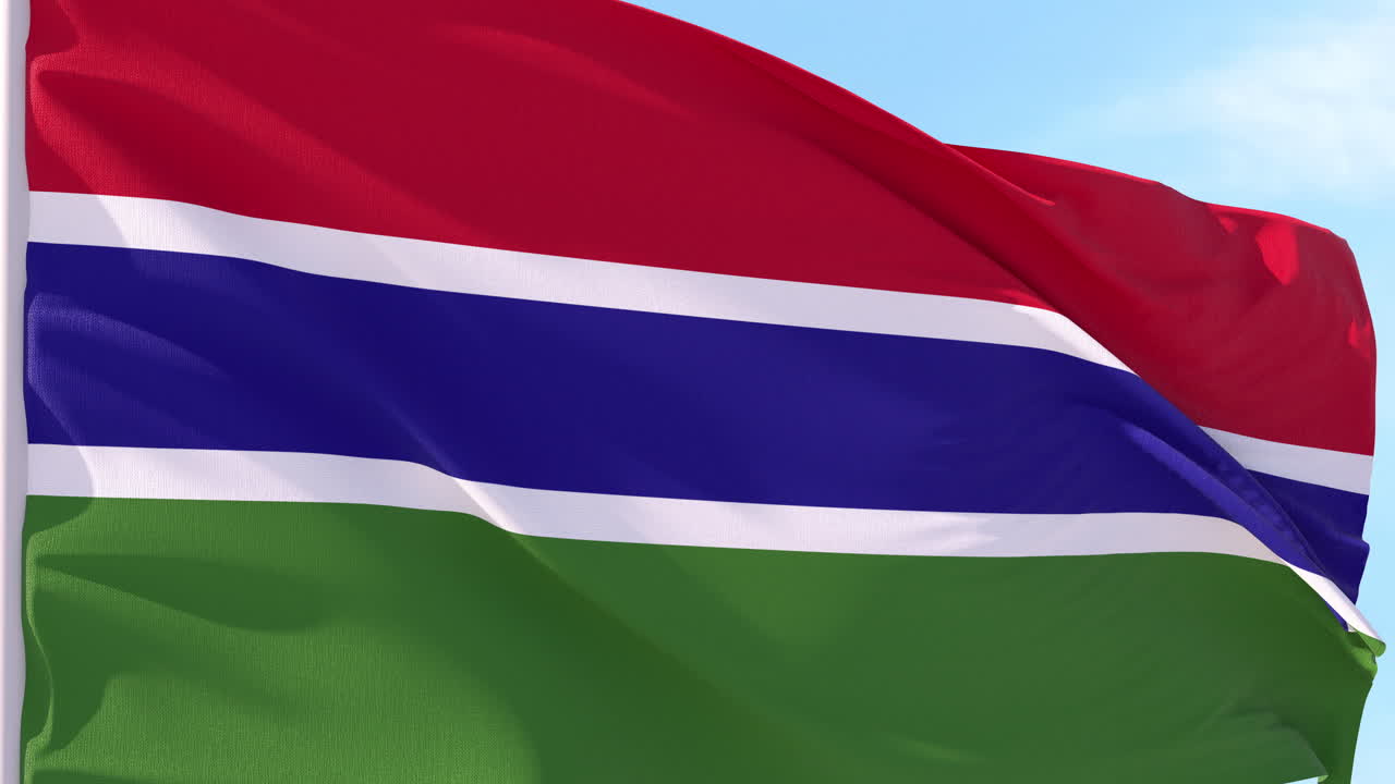 Gambian lippu liehuu tuulessa sinistä taivasta vasten