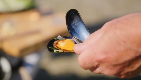 hand of a white man holding a open mussel in slowmotion