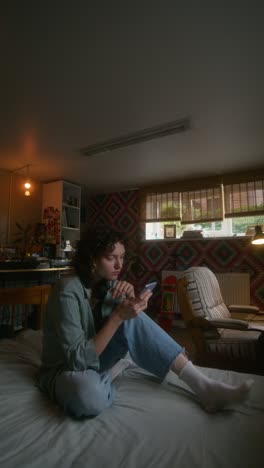 young woman using phone in a cozy bedroom