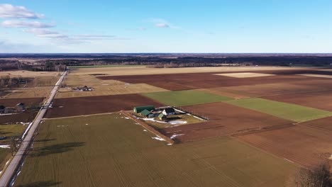 aerial dolly in over farmhouse and agriculture land at day, wide angle