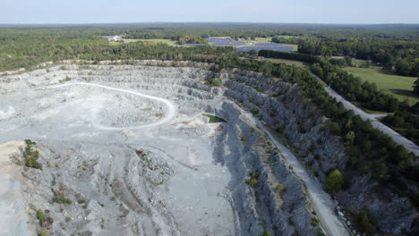 Aerial-drone-over-an-open-pit-mine,-solar-panels