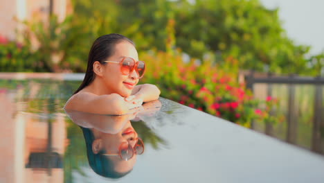 happy satisfied young asian woman enjoying in serenity of swimming pool tropical weather on holiday vacation, slow motion close up