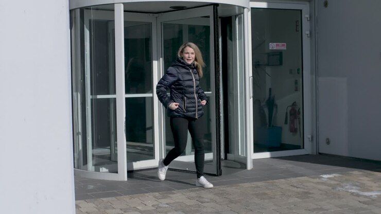 Female employee leaves office building through a revolving door after work