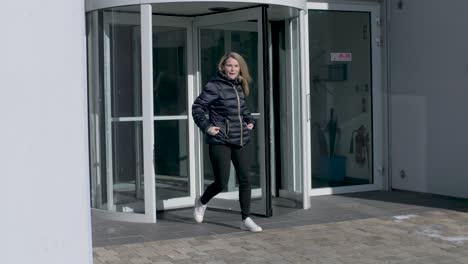 female employee leaves office building through a revolving door after work