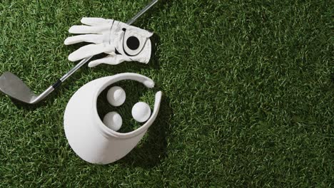 close up of golf club, balls, glove and peaked cap on grass, copy space, slow motion